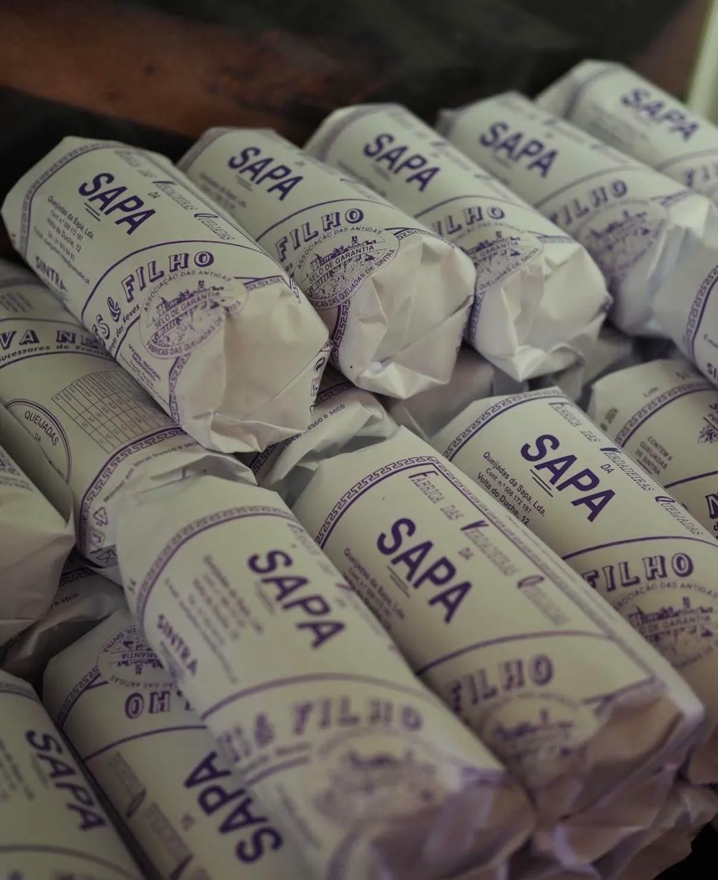 Pacote tradicional de 6 queijadas da Sapa, embaladas em rolo de papel timbrado.